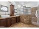 Elegant bathroom featuring dual sinks with dark wood cabinets, a glass block shower, and neutral tile flooring at 4625 E Villa Maria Dr, Phoenix, AZ 85032