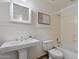 Well-lit bathroom featuring a pedestal sink, white wainscoting, a bathtub with shower, and neutral-colored flooring at 4625 E Villa Maria Dr, Phoenix, AZ 85032