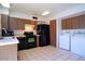 Cozy kitchen featuring tiled floors, brown cabinetry, and black appliances at 4625 W Thomas Rd # 71, Phoenix, AZ 85031