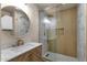 Modern bathroom featuring a vessel sink, a round mirror, and a shower with gold accents at 4913 E Acoma Dr, Scottsdale, AZ 85254