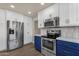 Modern kitchen featuring stainless steel appliances, stylish blue and white cabinetry, and sleek countertops at 4913 E Acoma Dr, Scottsdale, AZ 85254