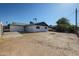 View of the backyard, featuring a white-painted home, partial fencing, and mature trees in the distance at 5336 W Lewis Ave, Phoenix, AZ 85035