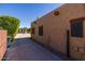 Exterior view showcasing textured stucco wall, dark window frames, and mature greenery along the walkway at 8675 S College Ln, Tempe, AZ 85284
