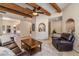 Spacious living room featuring beamed ceiling, leather seating, travertine floors, and decorative niches at 8675 S College Ln, Tempe, AZ 85284