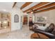 Open living area with beamed ceiling, leather furniture, travertine floors, and arched doorways at 8675 S College Ln, Tempe, AZ 85284