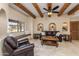 Cozy living room with beamed ceiling, leather furniture, window bench, and travertine floors at 8675 S College Ln, Tempe, AZ 85284