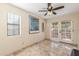 Sunlit office room with a ceiling fan, tile flooring, and french doors that lead to an outdoor balcony at 8675 S College Ln, Tempe, AZ 85284