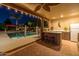 Covered outdoor kitchen and bar area overlooking a well lit pool and dining, creating a seamless blend of luxury at 8675 S College Ln, Tempe, AZ 85284