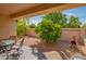 Private backyard patio with furniture, low-maintenance desert landscaping, mature trees, and a cozy fireplace at 8839 W Rimrock Dr, Peoria, AZ 85382