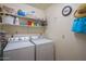 Functional laundry room with shelving for storage, a clock, and hanging space for accessories at 8839 W Rimrock Dr, Peoria, AZ 85382
