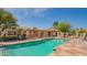 Community pool featuring a pergola with seating and BBQ area, surrounded by lush greenery at 8839 W Rimrock Dr, Peoria, AZ 85382