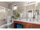 Bright bathroom with wooden vanity, shower, bathtub combination, and decorative wreath above toilet at 10130 S 185Th Dr, Goodyear, AZ 85338
