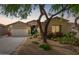 Charming single-story home with desert landscaping, a two car garage, and a beautiful tree at 10130 S 185Th Dr, Goodyear, AZ 85338