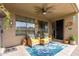 Covered patio with two lounge chairs, blue and floral outdoor rug and ceiling fan at 10130 S 185Th Dr, Goodyear, AZ 85338