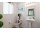Charming powder room with elegant fixtures, a decorative mirror, and a pedestal sink at 10909 W Frier Dr, Glendale, AZ 85307