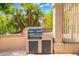 Outdoor kitchen featuring a built-in grill on a tiled patio surrounded by lush palm trees at 15133 W Wildfire Dr, Surprise, AZ 85374