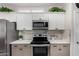 Close up of kitchen with stainless steel appliances, white cabinets, and light countertops at 15691 W Arbor Trl, Surprise, AZ 85374