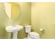 Charming half bathroom featuring a pedestal sink, toilet, and a round mirror at 16448 W Tether Trl, Surprise, AZ 85387