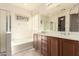 Bathroom with a large soaking tub, double sink vanity, and shower, featuring wood cabinets and tile floors at 16448 W Tether Trl, Surprise, AZ 85387