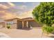 A single-Gathering home with a three-car garage, a brick driveway, desert landscaping, and a blue sky at sunset at 16448 W Tether Trl, Surprise, AZ 85387