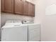 Functional laundry area with washer, dryer, and overhead cabinets for storage at 16448 W Tether Trl, Surprise, AZ 85387
