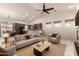 Open-concept living room with a fireplace, fan, and tile floor and a kitchen and dining room in the background at 16448 W Tether Trl, Surprise, AZ 85387