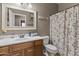 Bathroom featuring wood vanity with a white sink, toilet, shower curtain, and a decorative mirror at 21337 E Waverly Dr, Queen Creek, AZ 85142