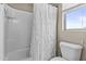 Tiled bathtub and shower combination with white shower curtain and a toilet located beside a window at 21337 E Waverly Dr, Queen Creek, AZ 85142