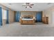 Relaxing bedroom featuring a large window, plush carpet, ceiling fan, and wood furniture at 21337 E Waverly Dr, Queen Creek, AZ 85142