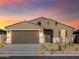 Sunset view of a charming single-story home featuring desert landscaping, and a two-car garage at 22514 W Tonopah Dr, Surprise, AZ 85387
