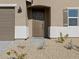 Close-up of a front door with an arched entryway, complemented by desert landscaping and a modern light fixture at 22514 W Tonopah Dr, Surprise, AZ 85387