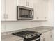 Modern kitchen showing gas range, granite countertops and stainless steel microwave in bright, white cabinetry at 22514 W Tonopah Dr, Surprise, AZ 85387