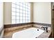 A soaking tub is surrounded by tile and features a window block for plenty of privacy and light at 2300 E Sanoque Ct, Gilbert, AZ 85298