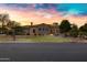 Stunning exterior of a stone and stucco home with circular tower, manicured lawn, and colorful sunset at 2300 E Sanoque Ct, Gilbert, AZ 85298