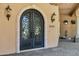 Close up of an ornate iron double front door and stone archway with sconces at entrance at 2300 E Sanoque Ct, Gilbert, AZ 85298