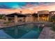 Relaxing backyard oasis featuring a sparkling pool, covered patio, and landscaped surroundings at 2300 E Sanoque Ct, Gilbert, AZ 85298