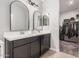 Bathroom with dual sinks, arched mirrors, and access to the walk in closet with clothing racks at 235 S 190Th Ave, Buckeye, AZ 85326