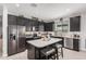 Modern kitchen features stainless steel appliances, a central island with barstool seating, and dark cabinets at 235 S 190Th Ave, Buckeye, AZ 85326