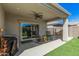 Covered patio features rocking chairs for outdoor relaxation, overlooking low-maintenance artificial turf in the backyard at 235 S 190Th Ave, Buckeye, AZ 85326