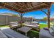 Outdoor living space featuring a pergola with comfy seating and artificial grass, and a swimming pool in the background at 235 S 190Th Ave, Buckeye, AZ 85326