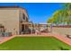 Landscaped backyard with artificial turf, seating, covered patio, and a luxurious pool in a private setting at 2454 W Camp River Rd, Queen Creek, AZ 85144