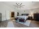 The main bedroom has wood flooring, a ceiling fan, a picture window, a large bed and storage spaces at 2454 W Camp River Rd, Queen Creek, AZ 85144