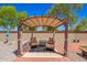 Cozy covered patio seating area in a lush, well-maintained backyard, perfect for outdoor living at 2454 W Camp River Rd, Queen Creek, AZ 85144