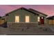 Charming single-story home with a red door and a well-maintained, low maintenance front yard at dusk at 2668 E San Miguel Dr, Casa Grande, AZ 85194