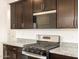 Close up of kitchen with stainless steel range, granite countertops, and dark wood cabinets at 2668 E San Miguel Dr, Casa Grande, AZ 85194