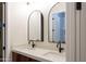 Bright bathroom showcasing a double vanity with arched mirrors and modern black fixtures at 3145 E Boot Track Trl, Gilbert, AZ 85296
