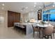 Contemporary kitchen showcases a spacious island with chairs and a dining table illuminated by modern lighting at 3145 E Boot Track Trl, Gilbert, AZ 85296