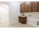 Well-lit laundry room featuring wooden cabinets, a sink, and utility hookups at 3145 E Boot Track Trl, Gilbert, AZ 85296