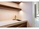Wet bar area with a stainless sink, gold faucet, and floating shelves at 3145 E Boot Track Trl, Gilbert, AZ 85296