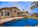 Inviting backyard featuring a pool with rock waterfall, covered patio, and lush artificial turf, perfect for relaxation at 3971 E Heather Ct, Gilbert, AZ 85234